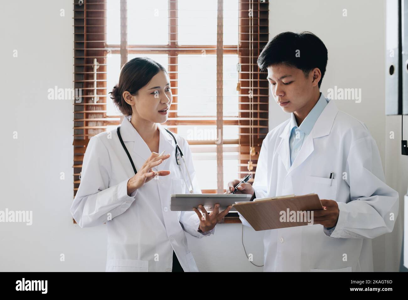 Portrait d'un médecin asiatique féminin et d'un médecin masculin utilisant un comprimé pour discuter des problèmes des patients avant le traitement Banque D'Images