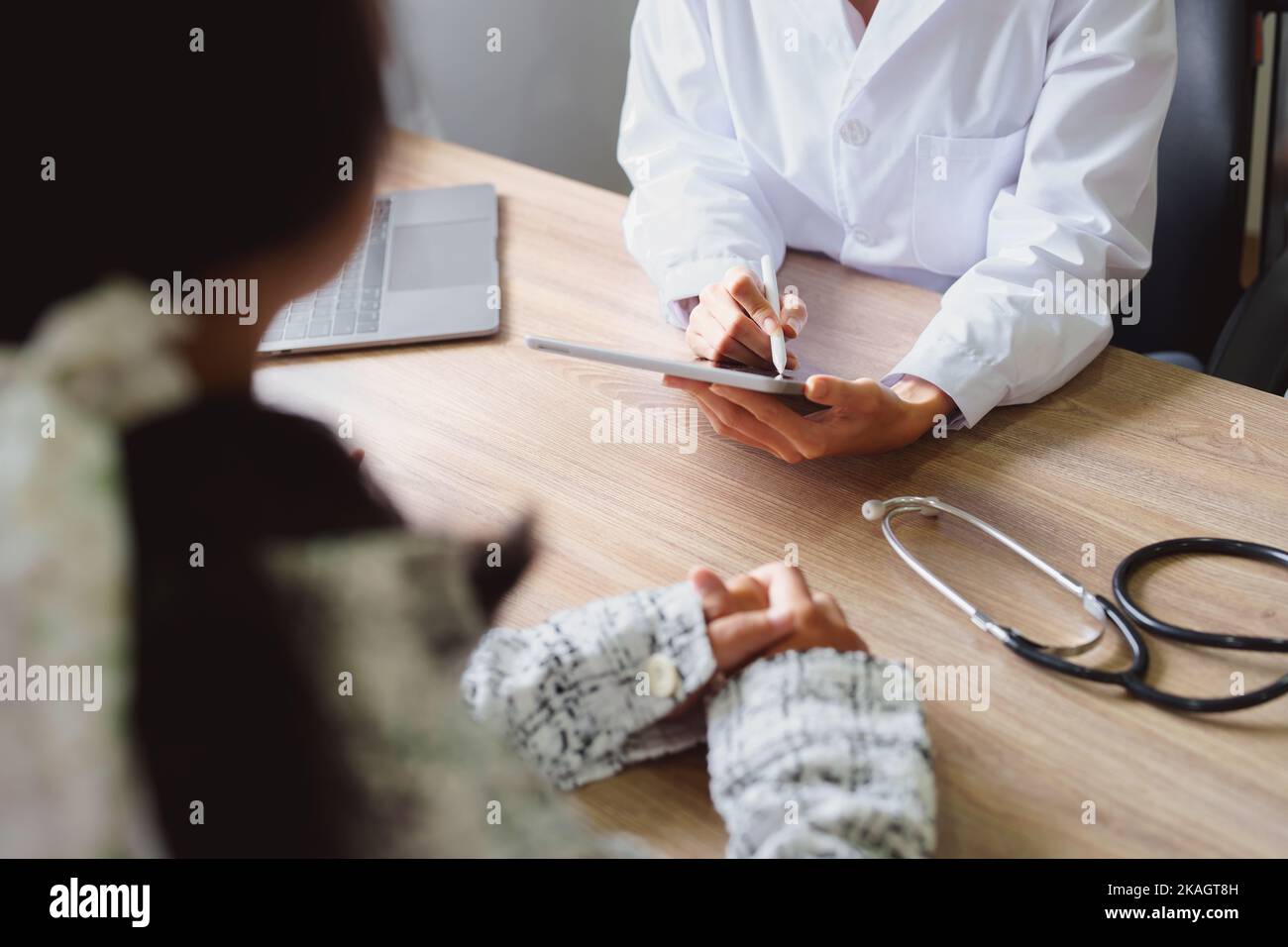 Portrait d'un médecin conseillant des clients sur des problèmes de santé tenant une tablette pour travailler et parlant aux patients qui viennent à un traitement Banque D'Images