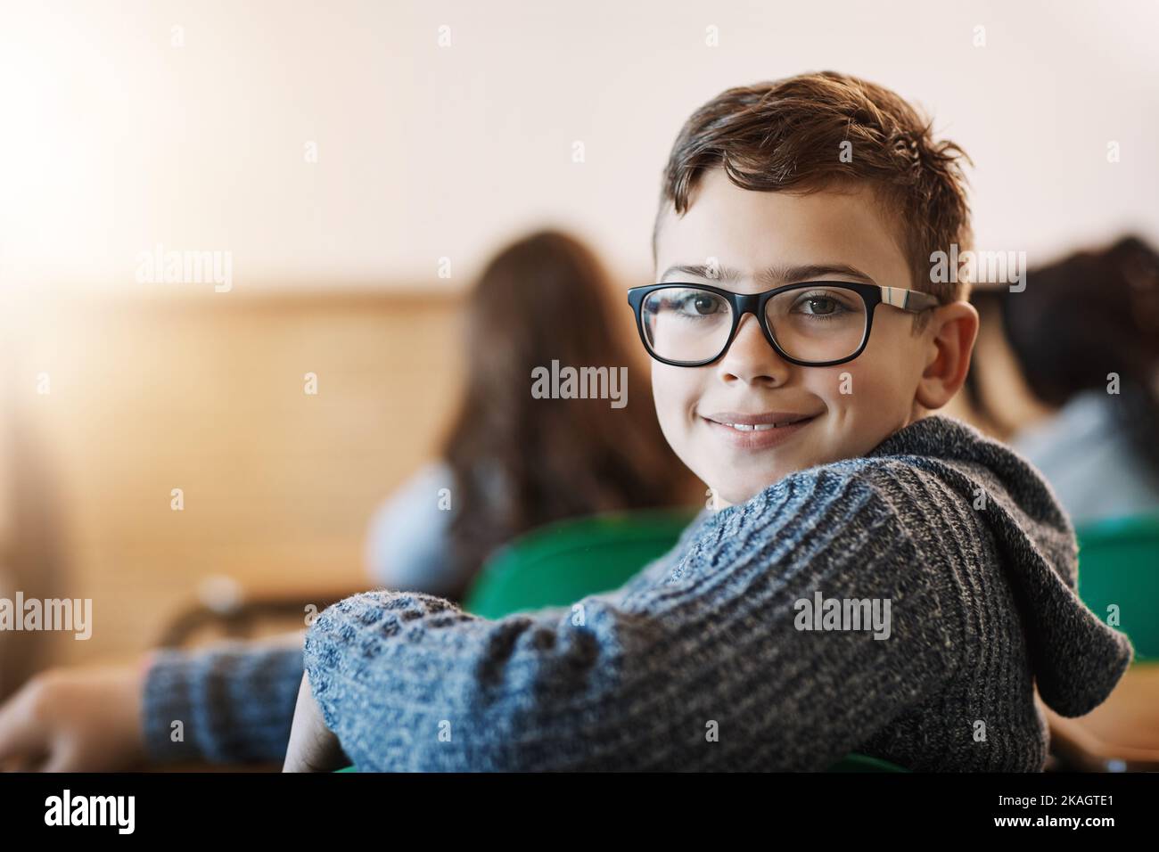 Heureux d'être en classe. Portrait arrière d'un garçon de l'école primaire assis dans la salle de classe. Banque D'Images