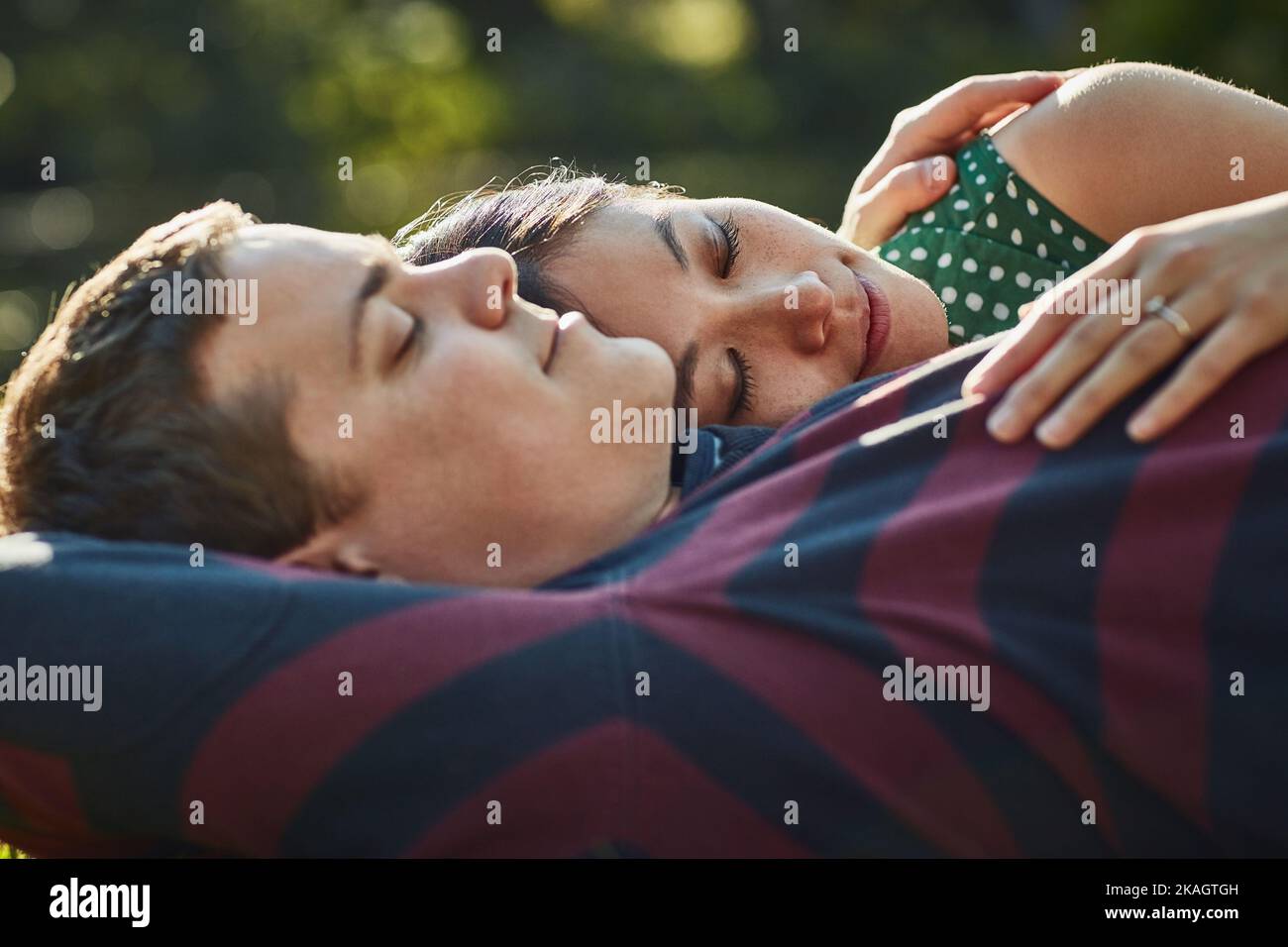 Gardez l'amour près du coeur. Un jeune couple affectueux qui profite d'une sieste dans le parc l'après-midi. Banque D'Images