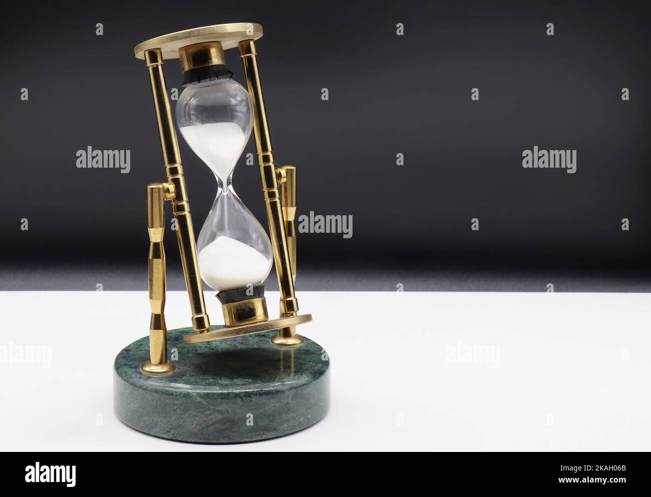 HourGlass sur table blanche isolée sur fond noir. Concept de dépassement de temps Banque D'Images
