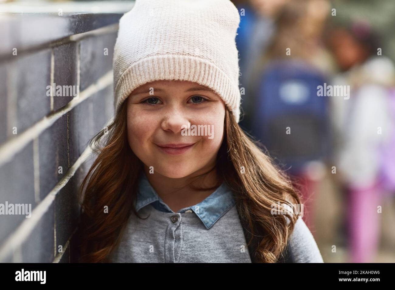 Souriant jusqu'à sa prochaine classe, une fille de l'école primaire dans le couloir de l'école. Banque D'Images