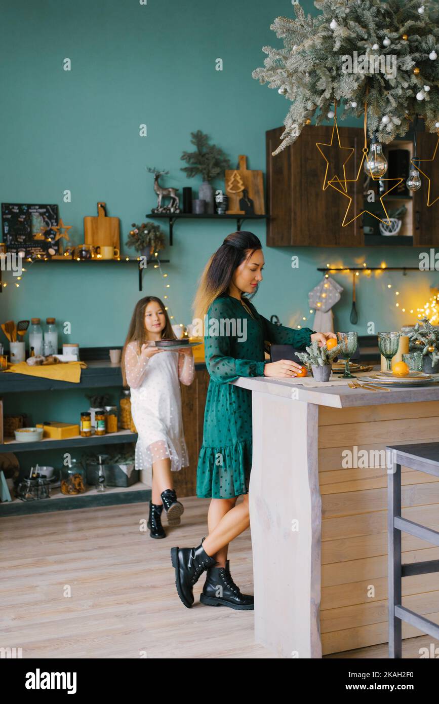La jeune mère et la petite fille regardent une tarte aux baies fraîchement cuite dans une cuisine de Noël décorée. Le concept des traditions familiales Banque D'Images