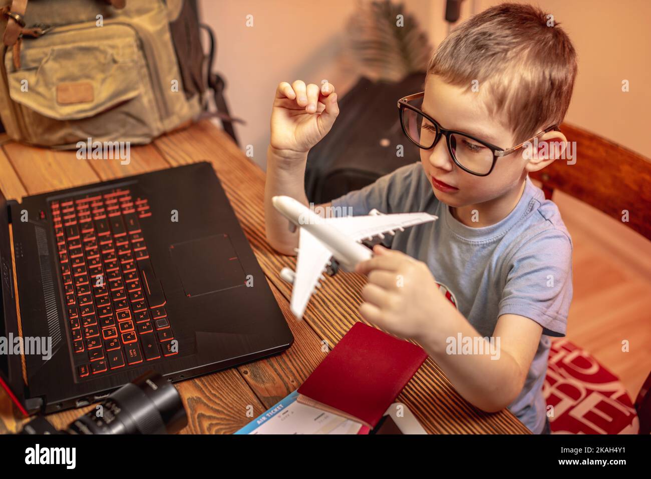 Un enfant achète des billets d'avion pour un ordinateur portable en ligne à la maison. Voyager est facile, même un enfant peut le manipuler. Banque D'Images