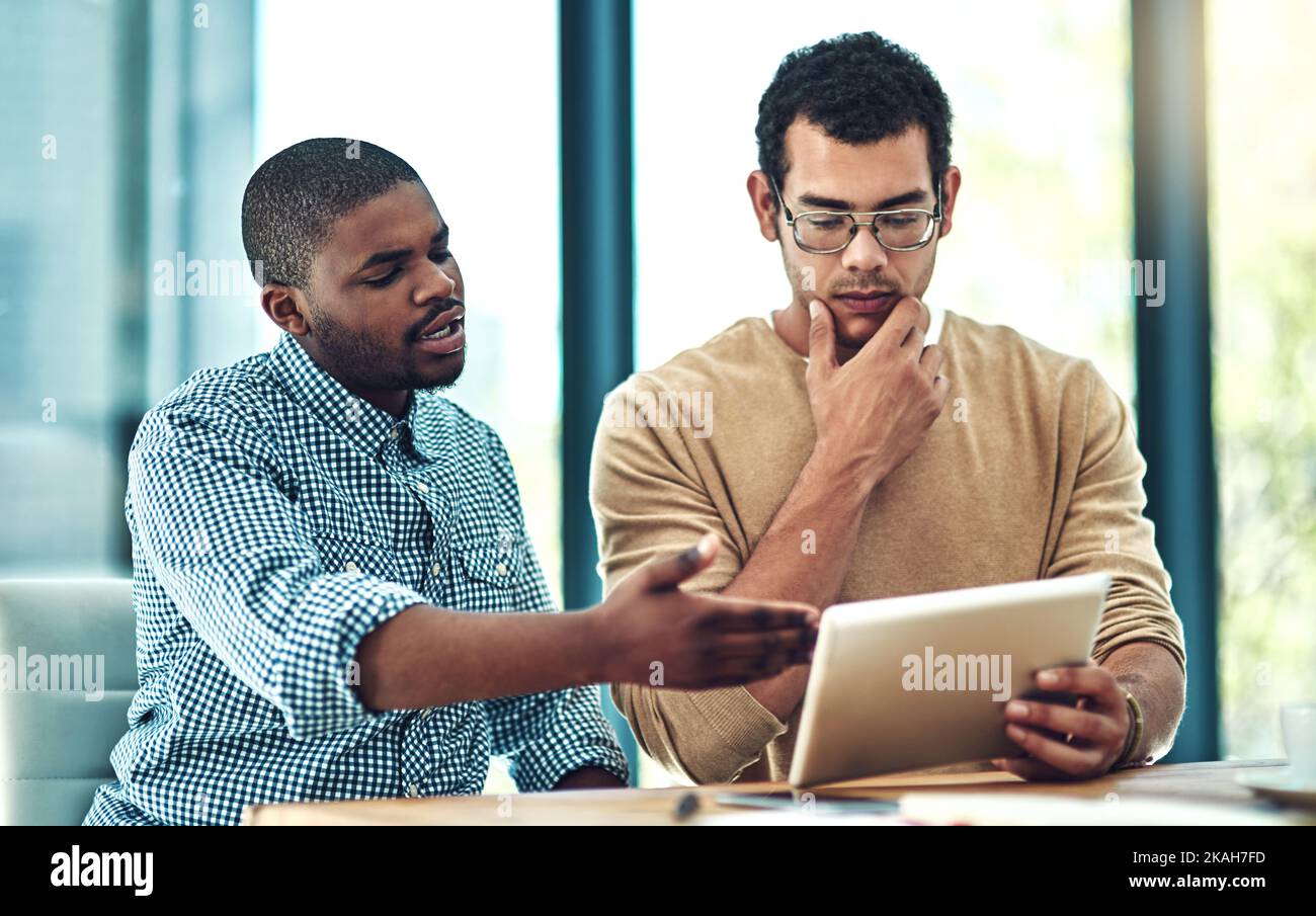 La technologie est la force motrice de notre succès. Deux jeunes concepteurs discutent de quelque chose sur une tablette numérique. Banque D'Images