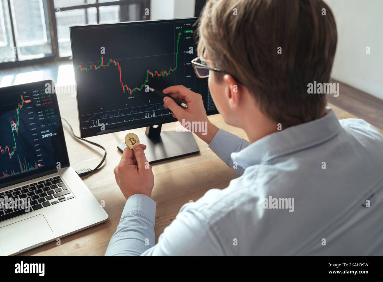 Homme d'affaires commerçant investisseur détenant des bitcoins d'or acheter ou vendre des jetons de crypto-monnaie, analysant le tableau des risques de marché boursier et d'investissement en ligne sur pc Banque D'Images