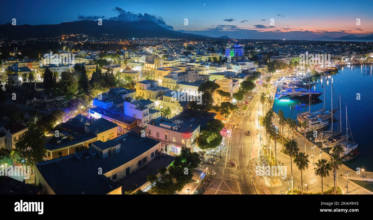 Port de Kos. Île de Kos, Grèce. Vue panoramique en début de soirée sur le lagon du port avec yachts et le centre touristique avec des promen éclairés Banque D'Images