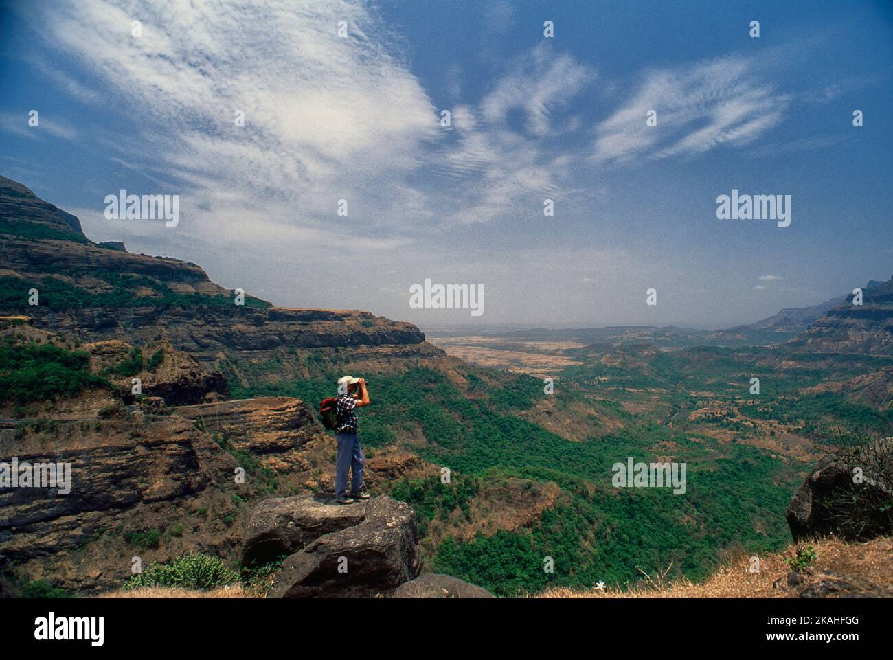 Trekker profitant de la vue sur la vallée de Malshejghat, l'ouest de la gamme de Hhats dans le district Thane-Pune de Maharashtra avec l'aide de binoculaire Banque D'Images