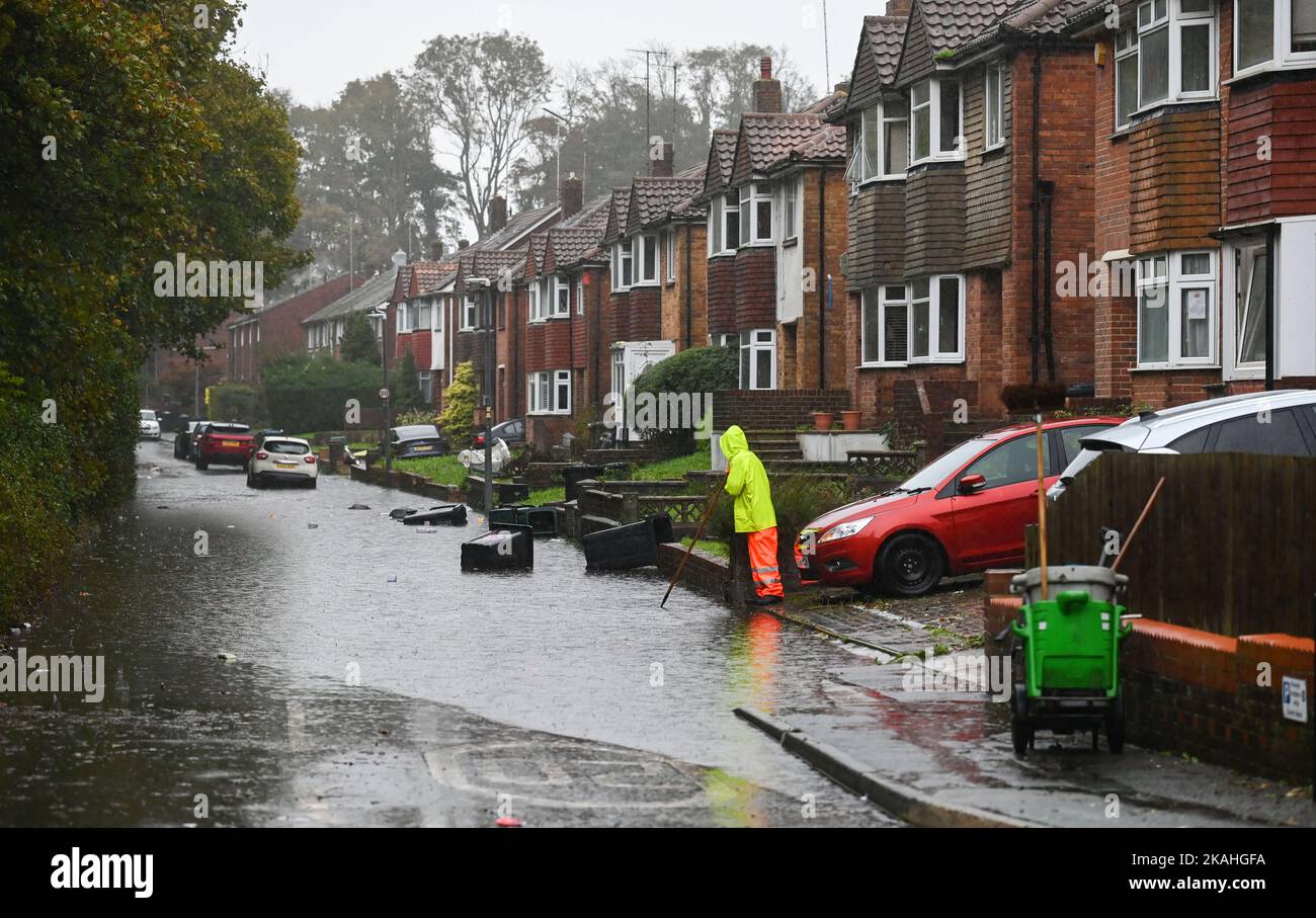 Brighton Royaume-Uni 3rd novembre 2022 - Un membre du conseil de l'état-major tente d'éliminer les eaux de crue dans une rue de Moulsecoomb , Brighton où des poubelles de déchets ménagers flottent aujourd'hui sur la route pendant les fortes pluies. : Crédit Simon Dack / Alamy Live News Banque D'Images