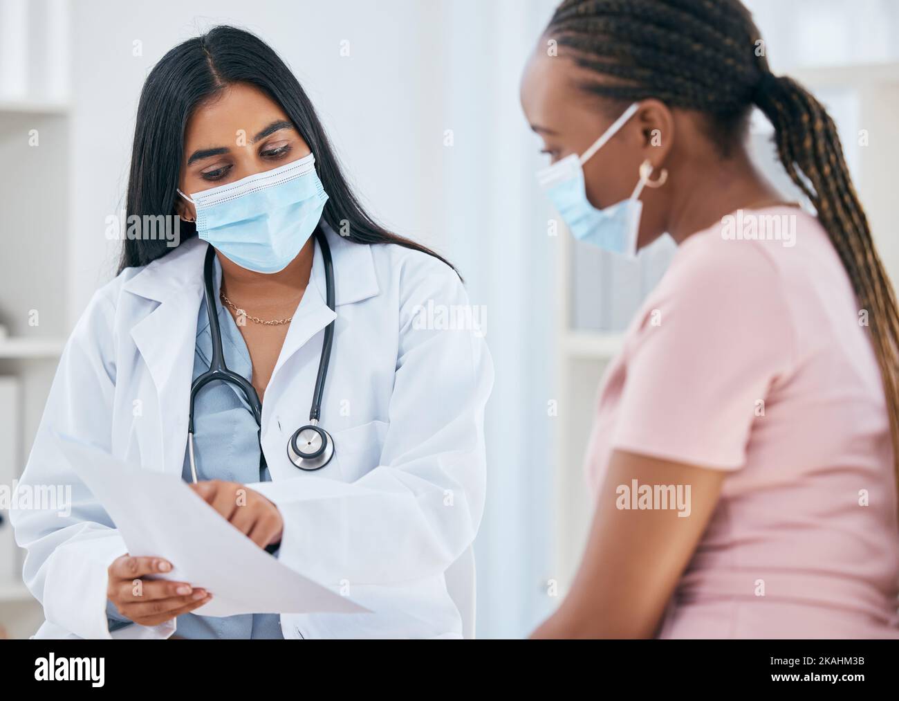 Médecin, masque Covid et femme patient médical résulte en une consultation de santé dans un bureau de clinique. Diversité des femmes dans un hôpital, une infirmière et Banque D'Images
