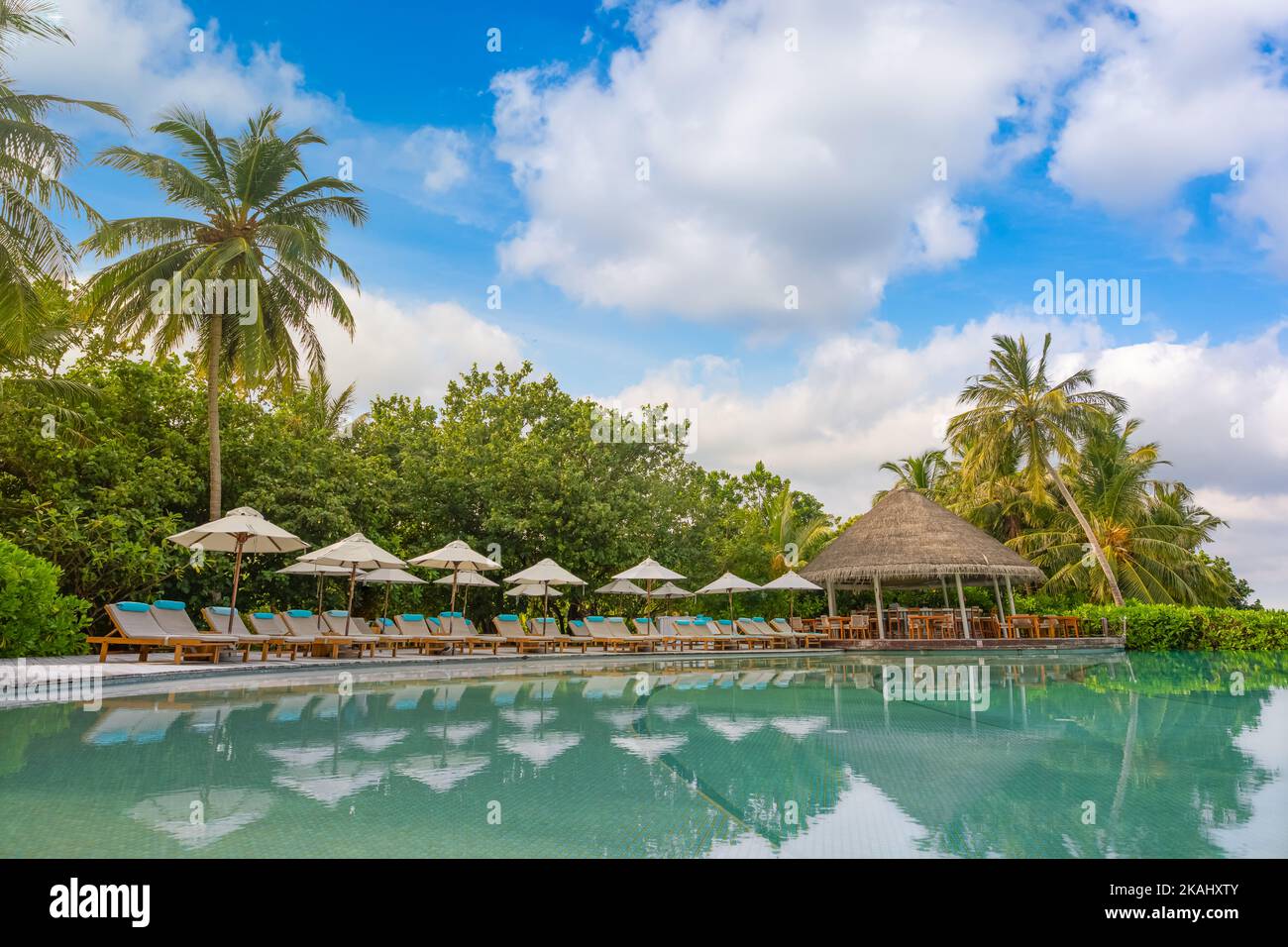 Parasol et chaise autour de la piscine à débordement près de la plage de l'océan à l'heure du lever ou du coucher du soleil. Pour les voyages de loisirs et de vacances concept station d'été Banque D'Images