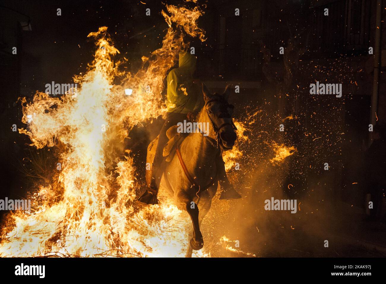 Un homme passe un cheval à travers un feu de joie lors du festival « Las Luminarias » sur 16 janvier 2017 à San Bartolome de Pinares, en Espagne. En l'honneur de Saint Anthony l'Abbé, le Saint patron des animaux, les chevaux sont criblés par les feux de joie la nuit précédant le jour officiel de l'honneur des animaux en Espagne. La tradition, qui a des centaines d'années, vise à purifier et à protéger l'animal au cours de l'année à venir. (Photo de Joaquin Gomez Sastre/NurPhoto) *** Veuillez utiliser le crédit du champ de crédit *** Banque D'Images