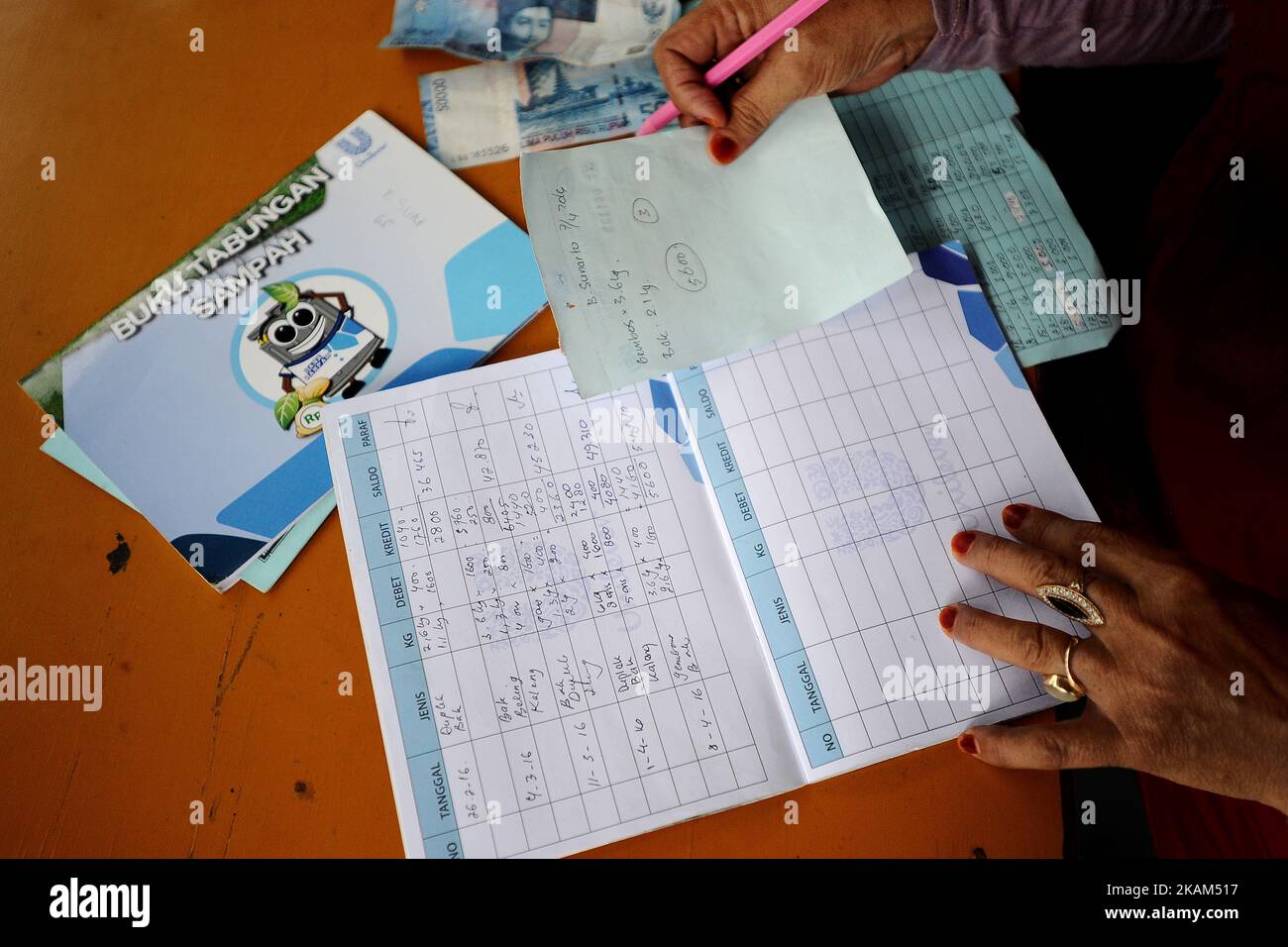 Une femme écrit sur la banque Sampah sauver livre. Bank Sampah (Garbage Bank) est une petite unité d'affaires dans la communauté de quartier exploitée par des femmes au foyer bénévoles. Ils collectent, trient et achètent les déchets non organiques des membres. Le gouvernement de la municipalité de Surabaya a mis au point un programme efficace d'éducation communautaire sur la gestion des déchets, du ménage au tri entre les déchets organiques et non organiques. Les programmes comprenaient Surabaya Green et Clean, Bank Sampah, compost House, centrale électrique de gazéification des déchets secs. (Photo par Robertus Pudyanto/NurPhoto) *** Veuillez utiliser le crédit du champ de crédit *** Banque D'Images