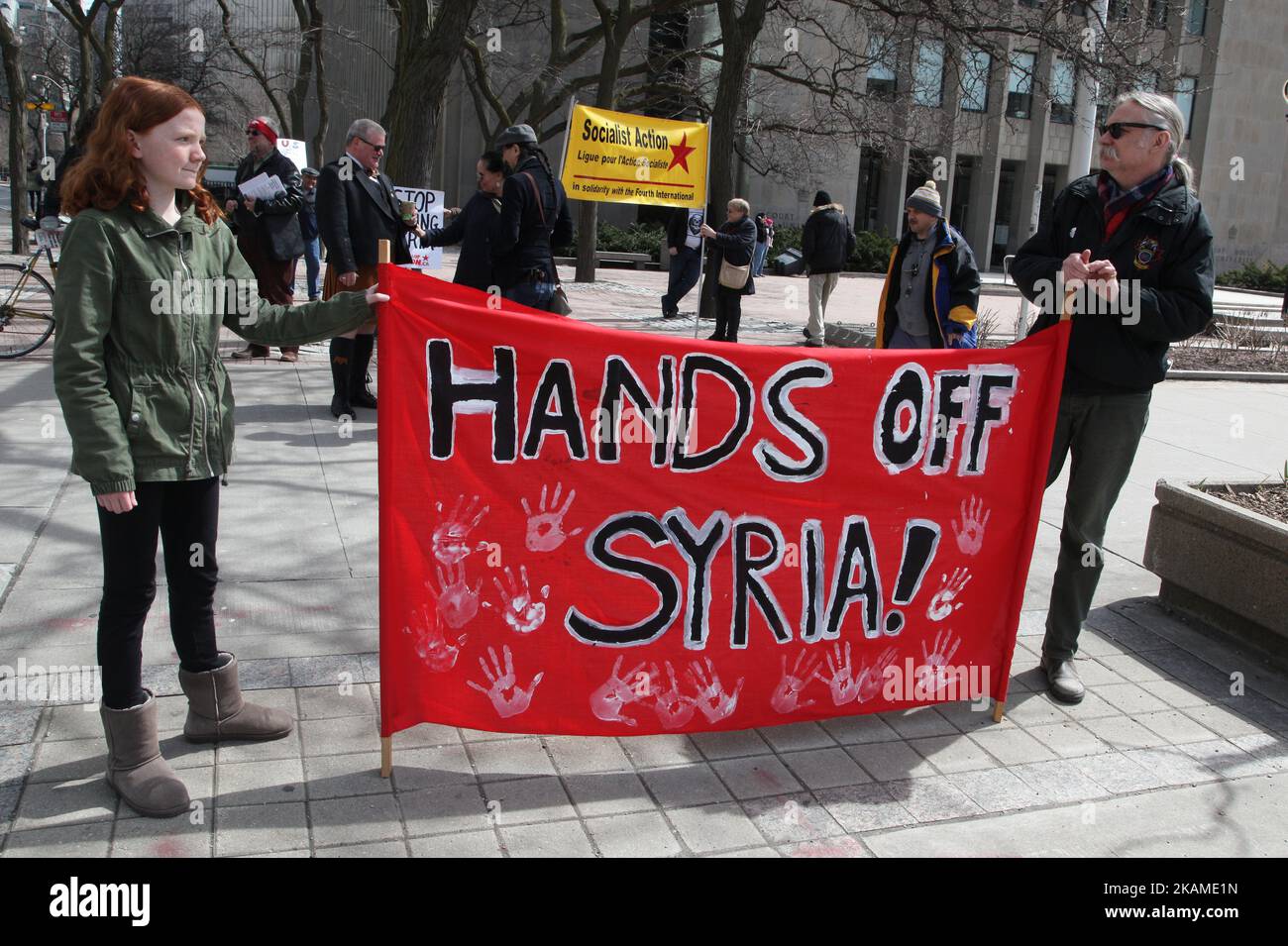 Les manifestants tiennent une bannière disant « Hands off Syria » lors d'une protestation contre la décision du président américain Donald Trump de lancer des frappes aériennes contre la Syrie sur 8 avril 2017 à Toronto, Ontario, Canada. Des manifestants se sont rassemblés devant le consulat américain de Toronto pour dénoncer les frappes aériennes de cette semaine contre le régime syrien. Les États-Unis ont lancé une frappe de missiles contre la Syrie pour la première fois depuis le début de la guerre civile, visant une base aérienne dans la petite ville d'Idlib à partir de laquelle les États-Unis revendiqueront cette semaine l'attaque d'armes chimiques contre des civils lancée par le régime de Bachar el-Assad. (Photo par Banque D'Images