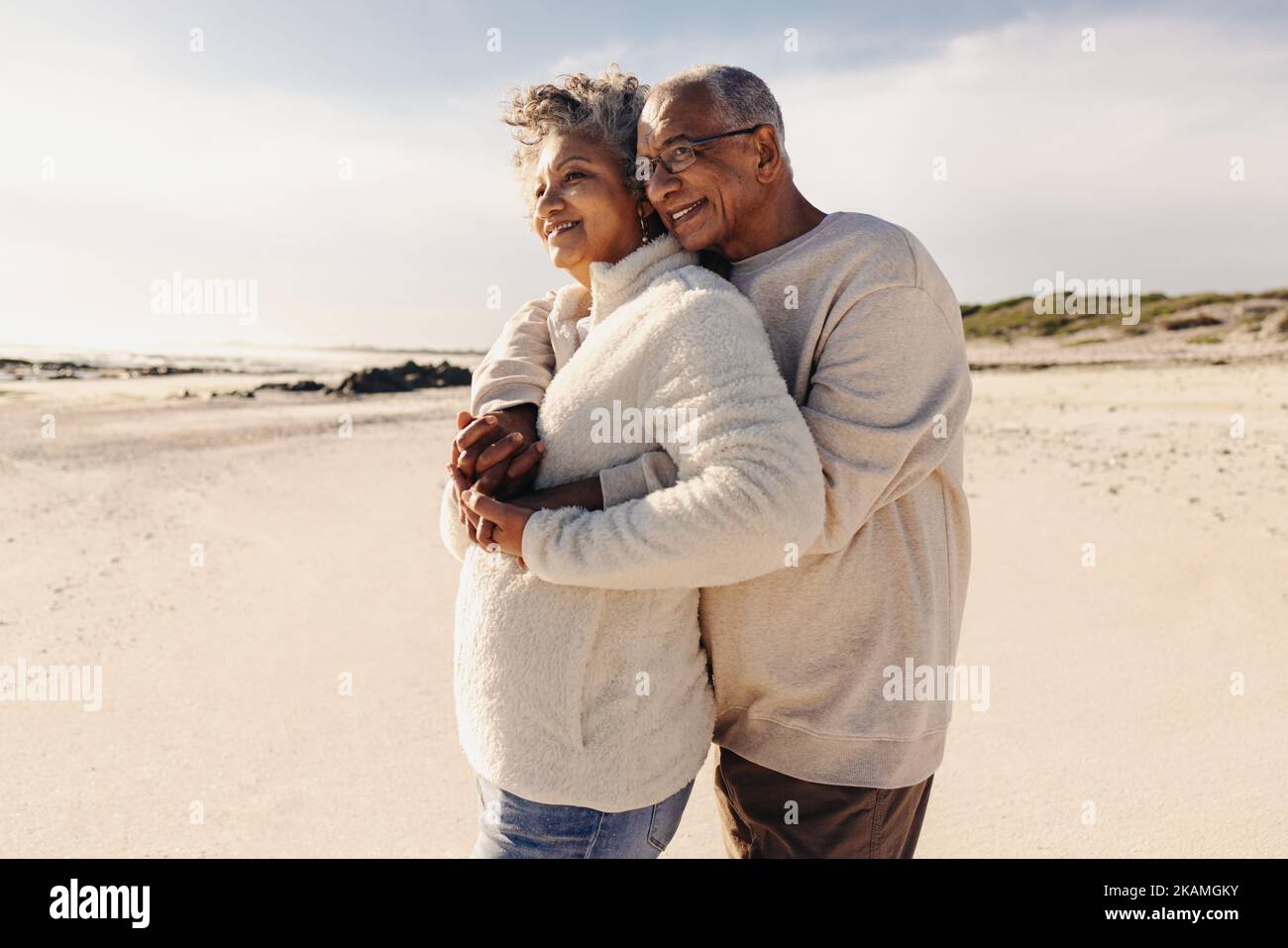 Couple d'âge mûr bénéficiant d'une vue rafraîchissante sur l'océan à la plage. Un couple senior heureux s'embrassant les uns les autres sur le sable de la plage. Vieux cou Banque D'Images