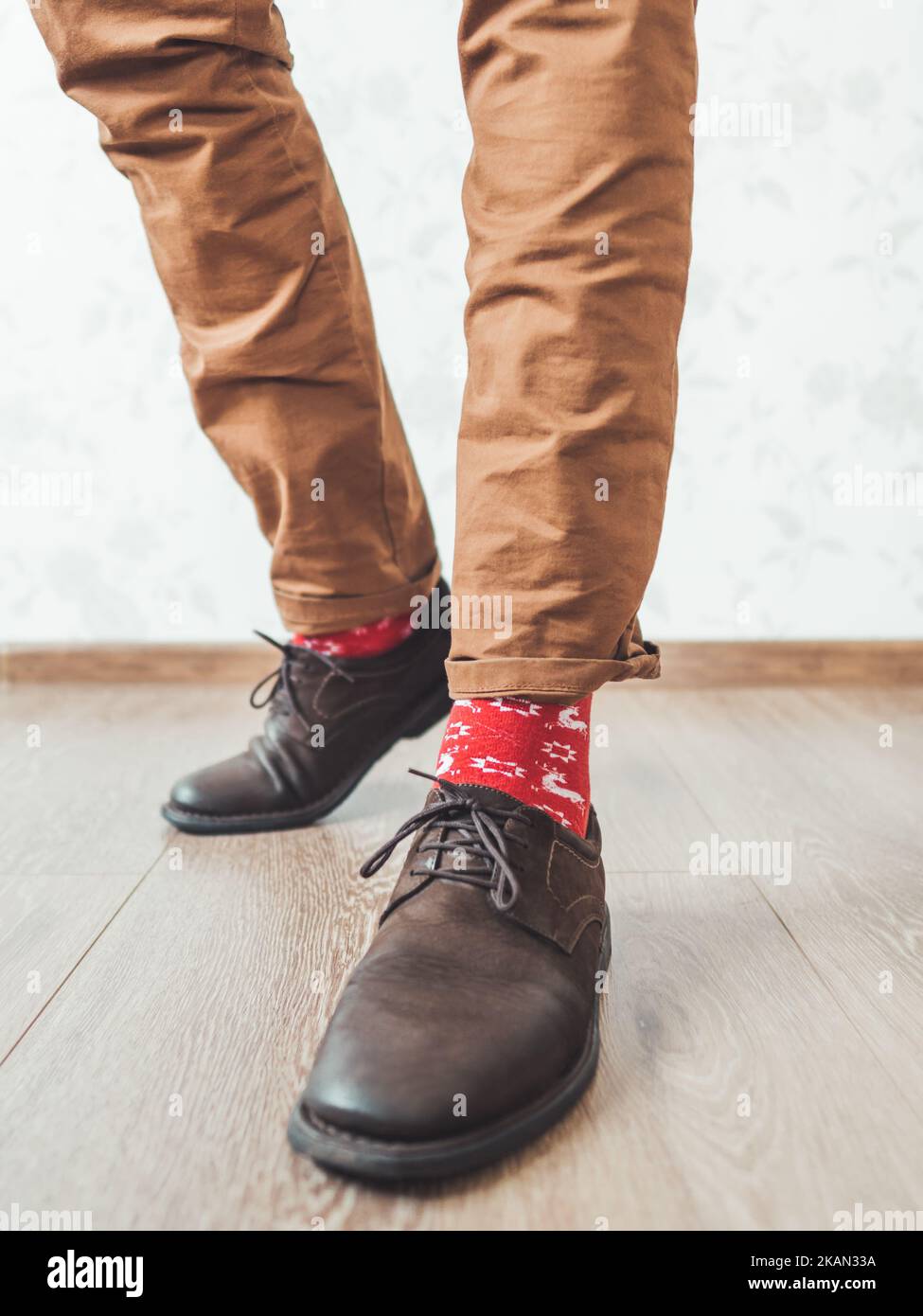 Le jeune homme tire la jambe de son pantalon de chino pour montrer des chaussettes rouges brillantes avec des rennes sur eux. Motif scandinave. L'esprit des vacances d'hiver. Décontracté Banque D'Images