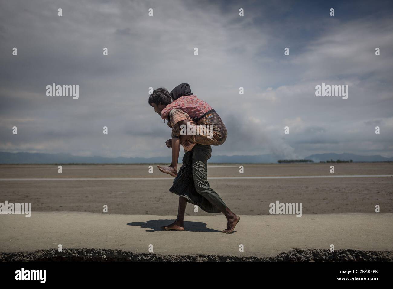 Un réfugié Rohingya porte sa mère sur le dos à Shahpirer DIP, Teknaf, Bangladesh; 14 septembre 2017. Le Bangladesh utilisera des troupes pour fournir une aide étrangère à la ville frontalière submergée par les réfugiés musulmans Rohingya du Myanmar, ont annoncé à la fin du 14 septembre. Cette décision fait suite à la critique des conditions chaotiques dans lesquelles les secours ont été distribués dans les immenses camps autour de Cox's Bazar, où environ 389 000 Rohingya de l'État Rakhine du Myanmar sont arrivés depuis 25 août. (Photo de Turjoy Chowdhury/NurPhoto) Banque D'Images