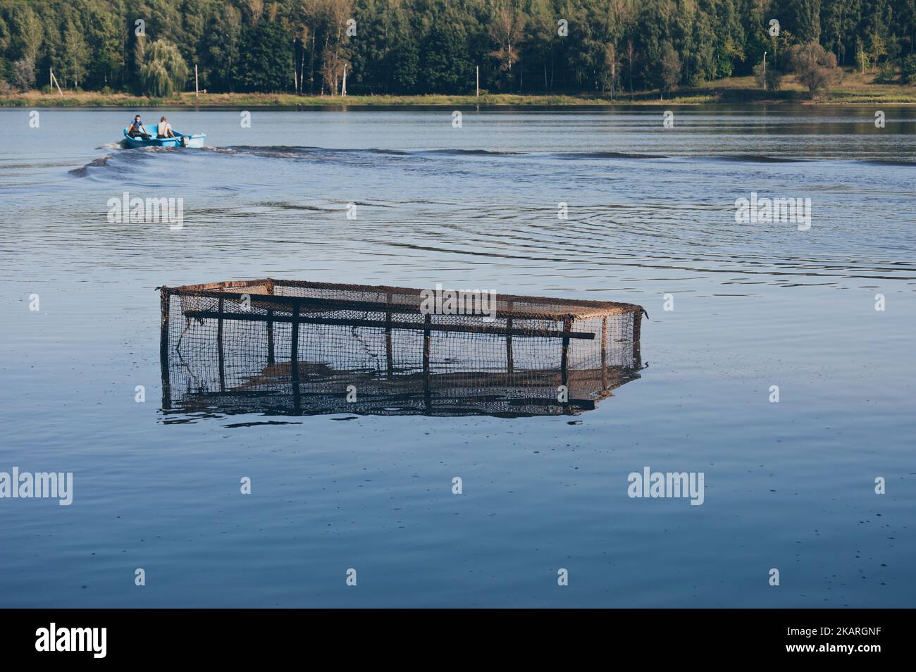 Filet de pêche dans l'eau, les hommes en bateau à moteur navigue sur la rivière Banque D'Images