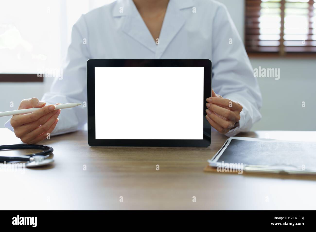 Le médecin asiatique tient la tablette d'ordinateur au client, l'écran blanc peut insérer du texte ou une image Banque D'Images