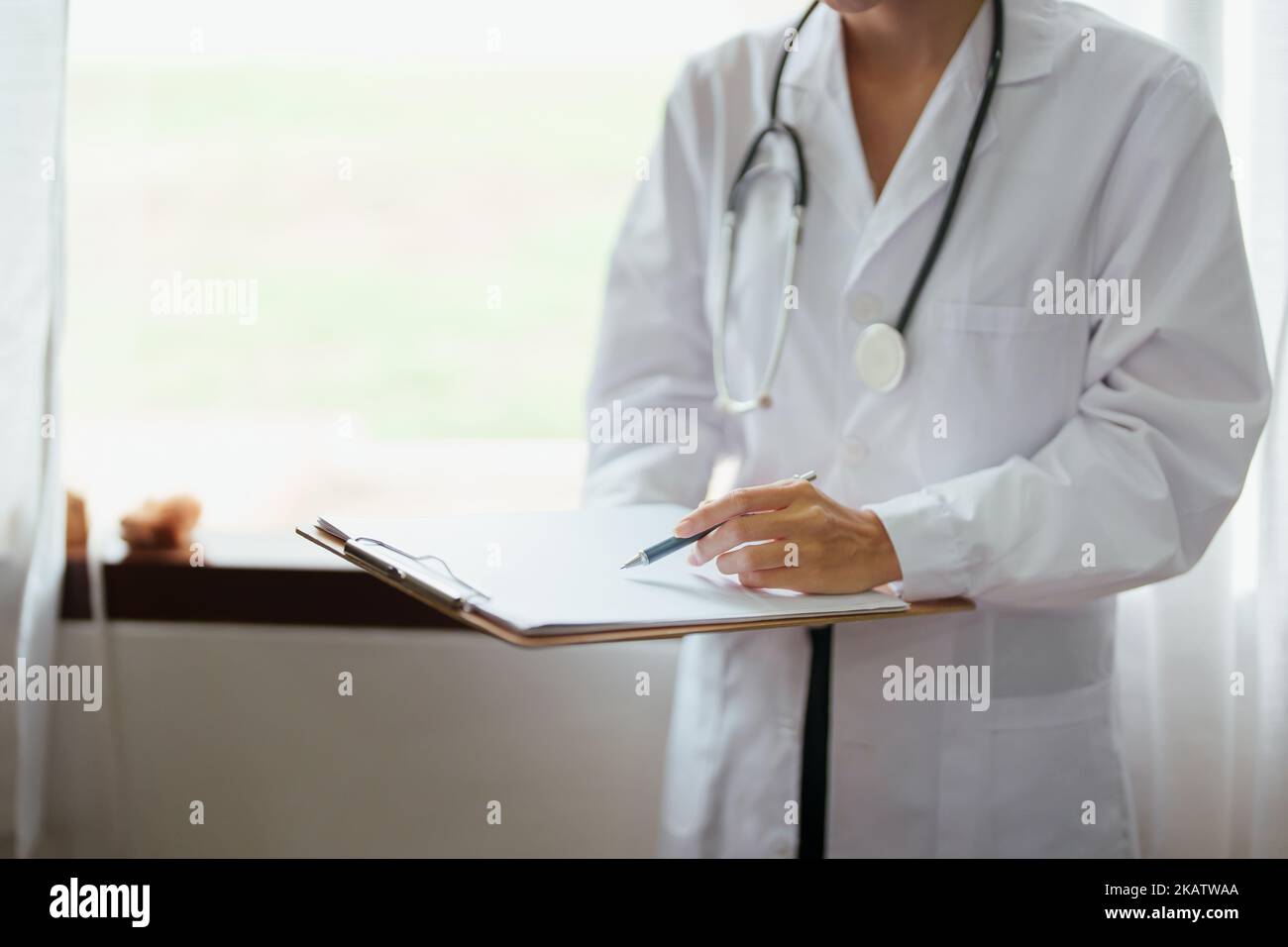 Femme asiatique médecin tenant un document d'information patient pour analyser le problème des maux avant examen Banque D'Images