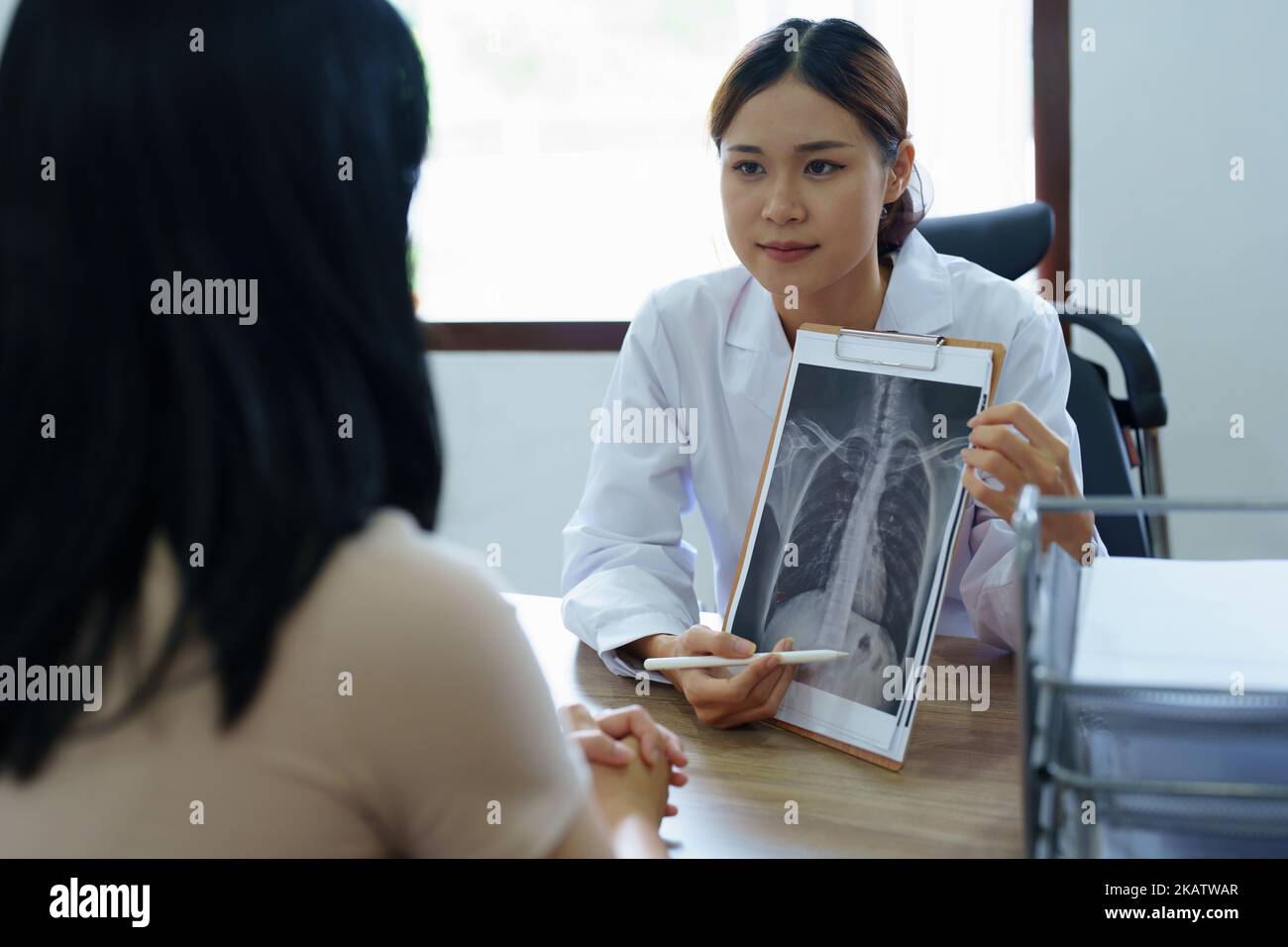 Une femme asiatique signale un film radiographique pour expliquer le processus de traitement du patient Banque D'Images