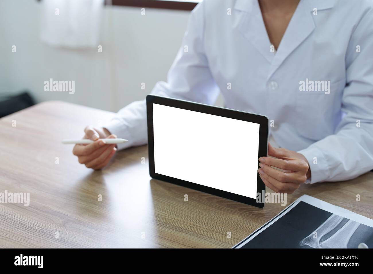 Le médecin asiatique tient la tablette d'ordinateur au client, l'écran blanc peut insérer du texte ou une image Banque D'Images