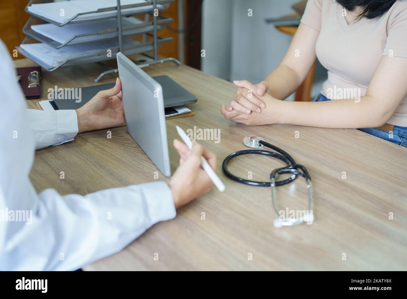 Une femme asiatique médecin montre au patient une tablette d'ordinateur pour voir le coût de la chirurgie avant le traitement Banque D'Images
