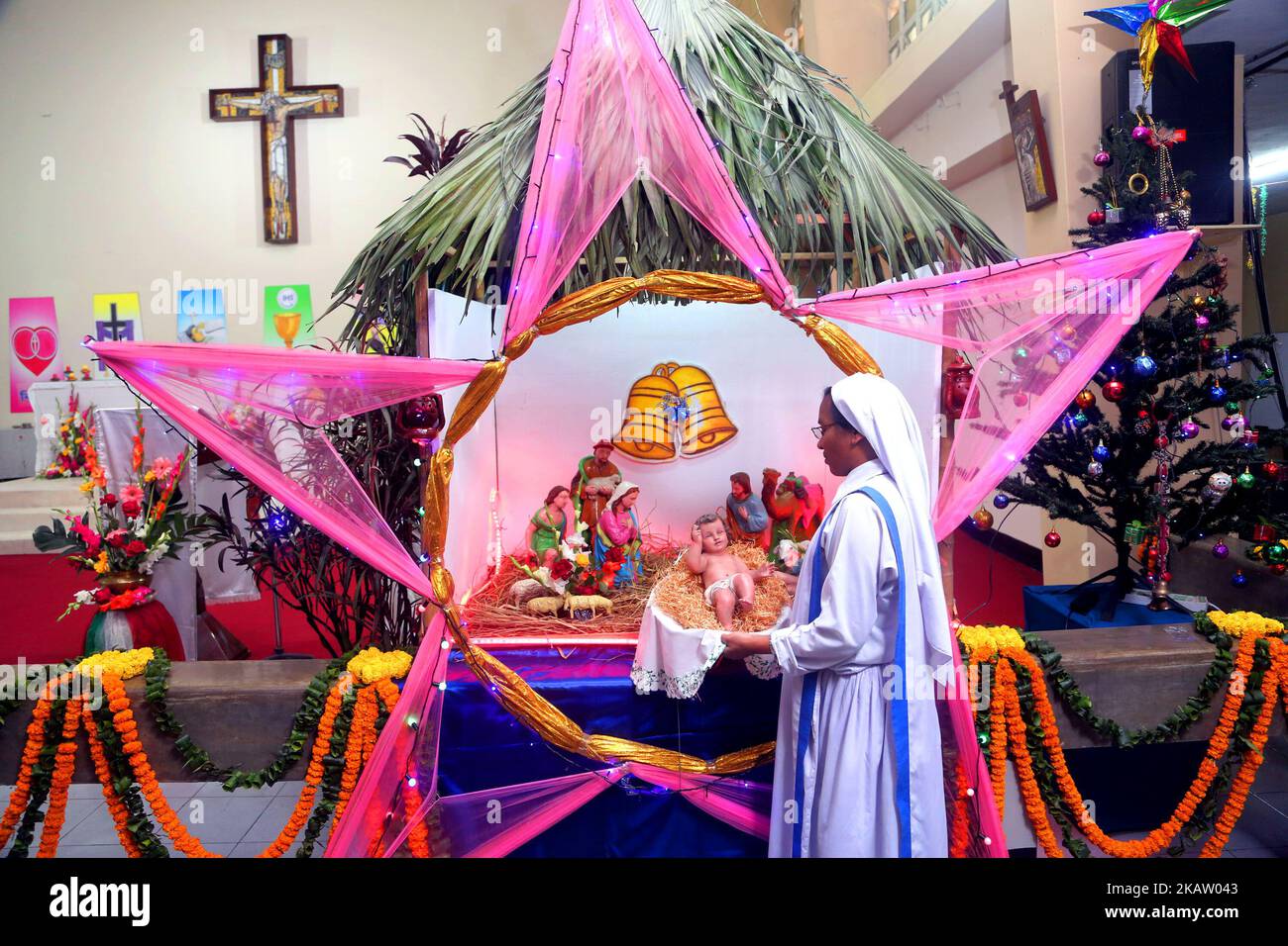 Une nonne tient le petit Jésus Christ dans une mangeoire à la cathédrale Sainte-Marie de Kakrail à Dhaka, le dimanche 24 décembre 2017, à la veille de Noël. La communauté chrétienne célèbre le jour de Noël au Bangladesh demain avec la fête commémorant l'anniversaire de Jésus Christ comme ailleurs dans le monde. Les chrétiens de différents groupes célébreront le festival dans le cadre de la ferveur religieuse et de la fête offrant des prières spéciales, éclairant les églises, Installer des arbres de Noël improvisés dans les maisons et les lieux de culte et les missions. (Photo de Sony Ramany/NurPhoto) Banque D'Images