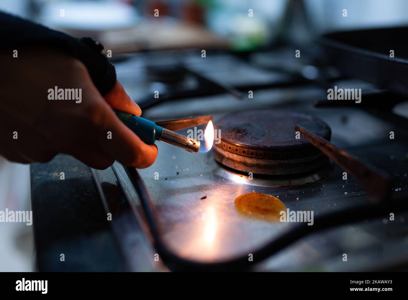 Une main est vue tenant un briquet tout en allumant le brûleur à gaz d'une cuisinière de cuisine. En raison de l'invasion de l'Ukraine par la Russie, les prix du gaz ont atteint leur niveau de récupération Banque D'Images
