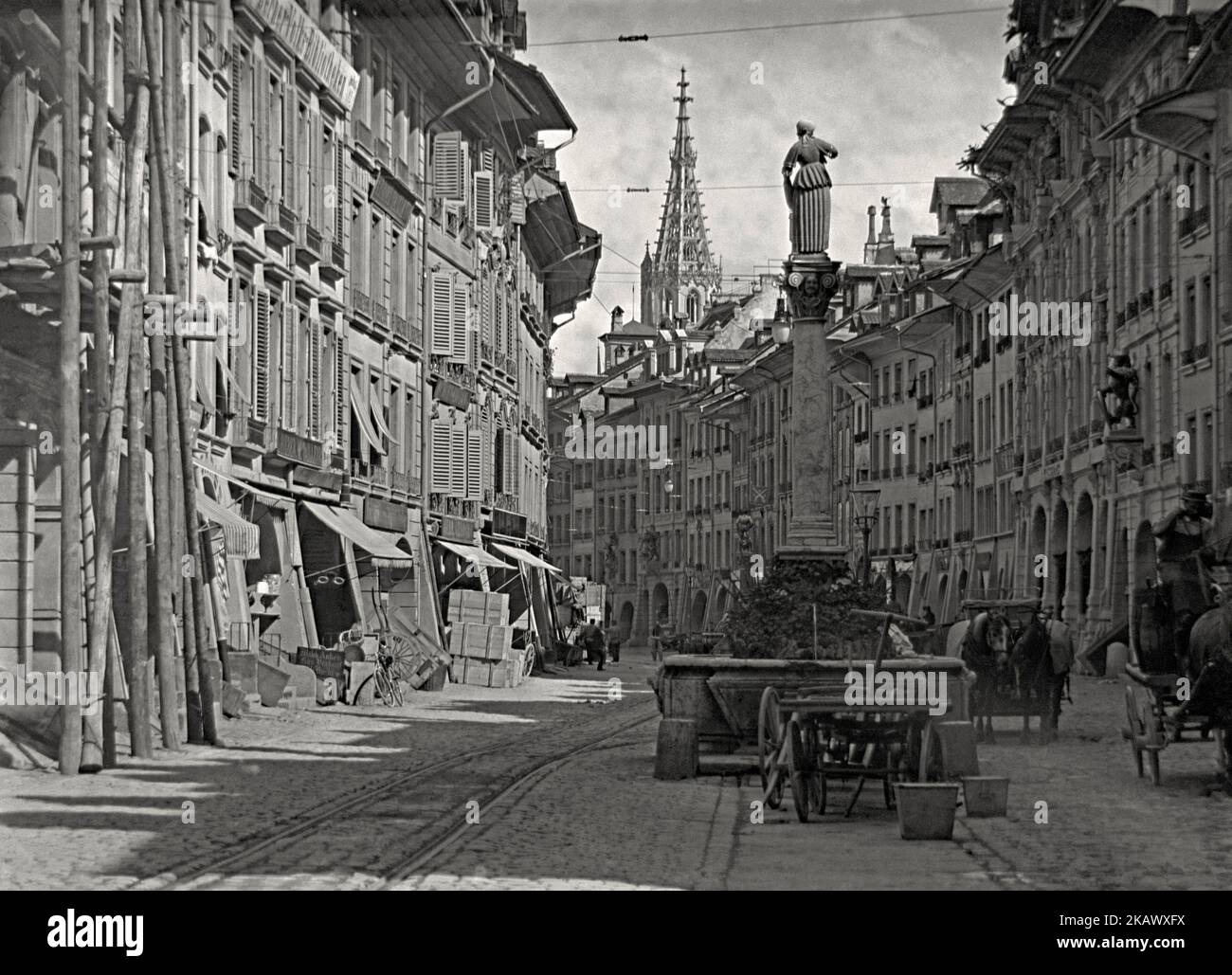 Une scène de rue sur Marktgasse dans la "vieille ville", Berne, Suisse, c. 1900. La Anna-Seiler-Brunnen (Fontaine Anna Seiler) est une fontaine est centre. Des magasins et des commerçants bordent la rue et le cheval et le chariot constituent un mode de transport important, mais des voies de tramway et le câblage aérien associé sont également visibles. La fontaine est dédiée à Anna Seiler, la fondatrice du premier hôpital de Berne. Anna Seiler a fondé un hôpital dans sa maison. Cette image provient d'un vieux négatif en verre, une photographie victorienne vintage. Banque D'Images