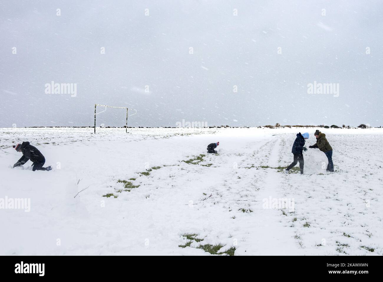 Les gens qui roulent des boules de neige pour faire le bonhomme de neige au parc sud de Galway qui était couvert de neige vendredi, 2 mars 2018, à Galway, en Irlande. Une explosion de temps sibérien surnommée « la Bête de l'est » a couvert l'Irlande de neige. L'Irlande pourrait voir sa pire neige depuis 1982. (Photo de Szymon Barylski/NurPhoto) Banque D'Images