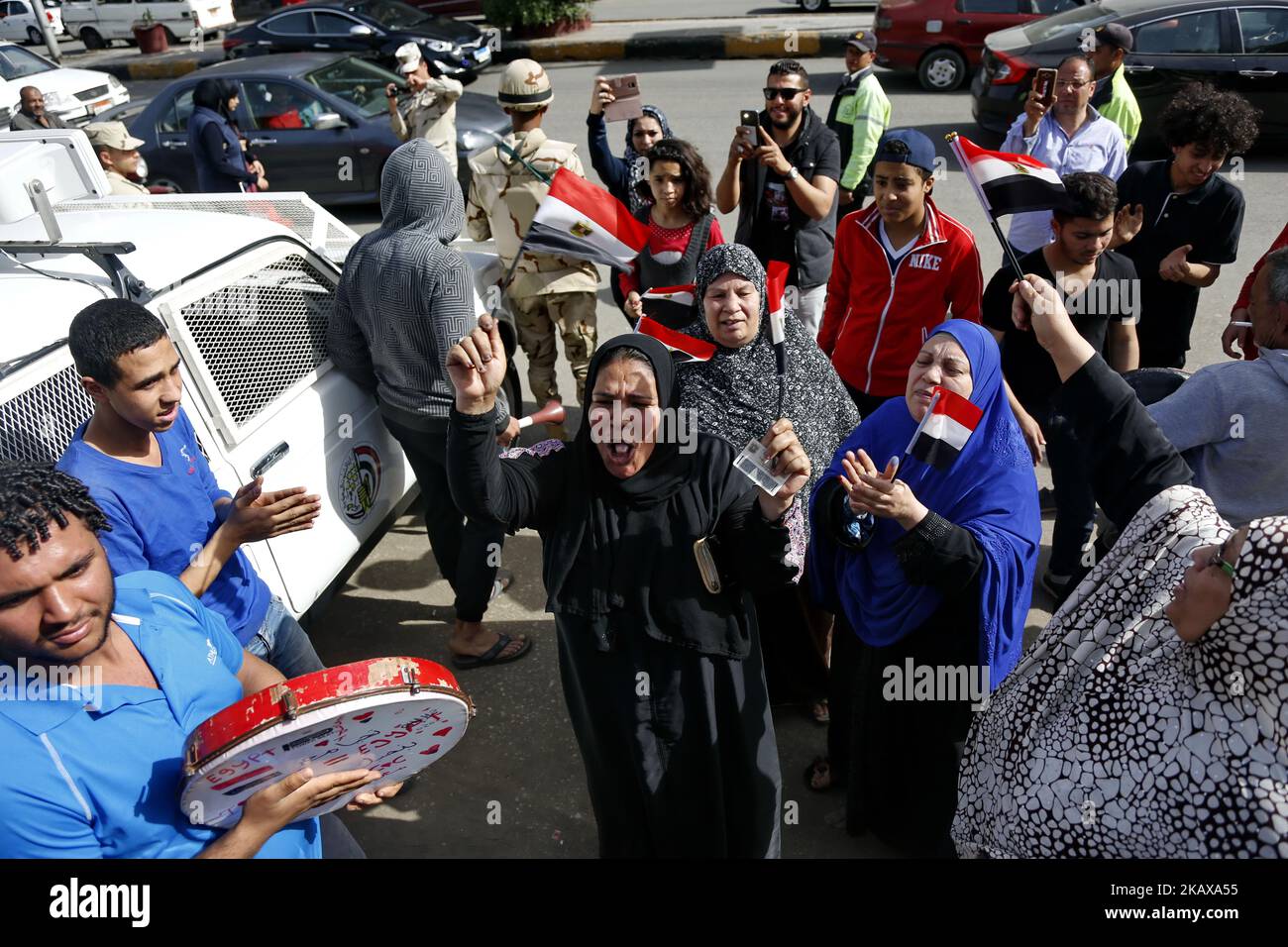 Les Égyptiens dansent et célèbrent avec des drapeaux nationaux tandis que certains portent des tee-shirts représentant le président sortant Abdel Fattah al-Sisi, devant un bureau de vote dans le quartier D'EL-Dokki, dans le district de Giza, la capitale du Caire, le premier jour des élections présidentielles de 2018 sur 26 mars 2018. (Photo par Islam Safwat/NurPhoto) Banque D'Images