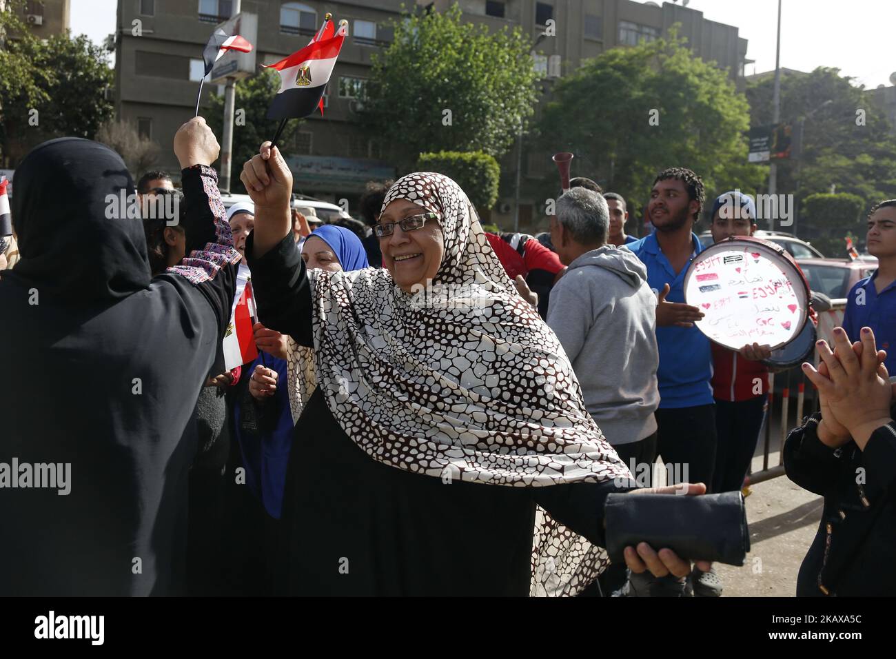 Les Égyptiens dansent et célèbrent avec des drapeaux nationaux tandis que certains portent des tee-shirts représentant le président sortant Abdel Fattah al-Sisi, devant un bureau de vote dans le quartier D'EL-Dokki, dans le district de Giza, la capitale du Caire, le premier jour des élections présidentielles de 2018 sur 26 mars 2018. (Photo par Islam Safwat/NurPhoto) Banque D'Images
