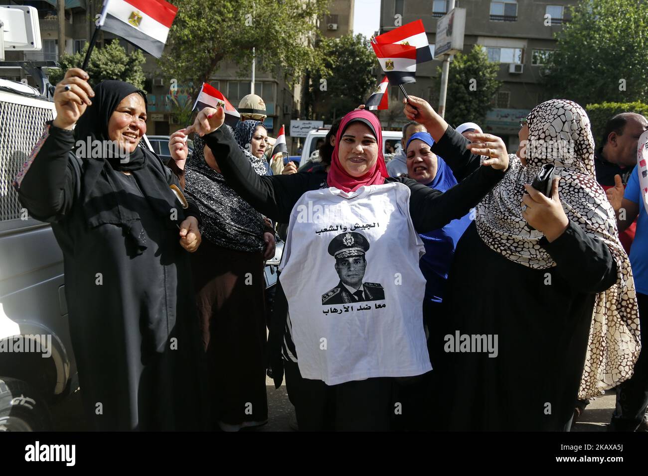 Les Égyptiens dansent et célèbrent avec des drapeaux nationaux tandis que certains portent des tee-shirts représentant le président sortant Abdel Fattah al-Sisi, devant un bureau de vote dans le quartier D'EL-Dokki, dans le district de Giza, la capitale du Caire, le premier jour des élections présidentielles de 2018 sur 26 mars 2018. (Photo par Islam Safwat/NurPhoto) Banque D'Images