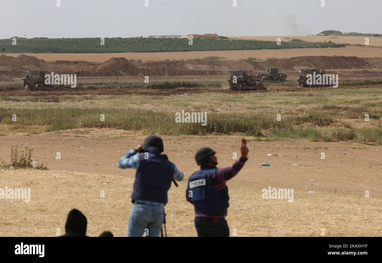 Les Palestiniens regardent les machines militaires israéliennes qui travaillent à la frontière entre Israël et la bande de Gaza, à la périphérie de la ville de Gaza, à 11 avril 2018. L'armée israélienne a déclaré qu'elle avait tiré sur des « cibles militaires » non spécifiées du Hamas à Gaza après une attaque à la bombe palestinienne sur une unité de génie militaire travaillant dans le territoire contrôlé par le Hamas. Aucun israélien n'a été blessé dans l'explosion, que la station de radio de l'armée a déclaré avoir ciblé un creuseur mécanique. (Photo de Majdi Fathi/NurPhoto) Banque D'Images