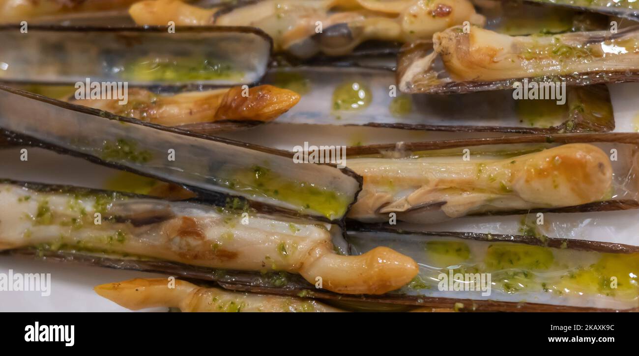 Deliciosa raciÃ³n de navajas a la plancha con aceite de oliva virgen extra y peregil en un restaurante Banque D'Images