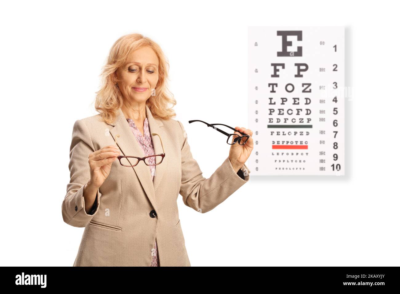 Femme comparant deux paires de lunettes de vue en face d'un test de vision isolé sur fond blanc Banque D'Images