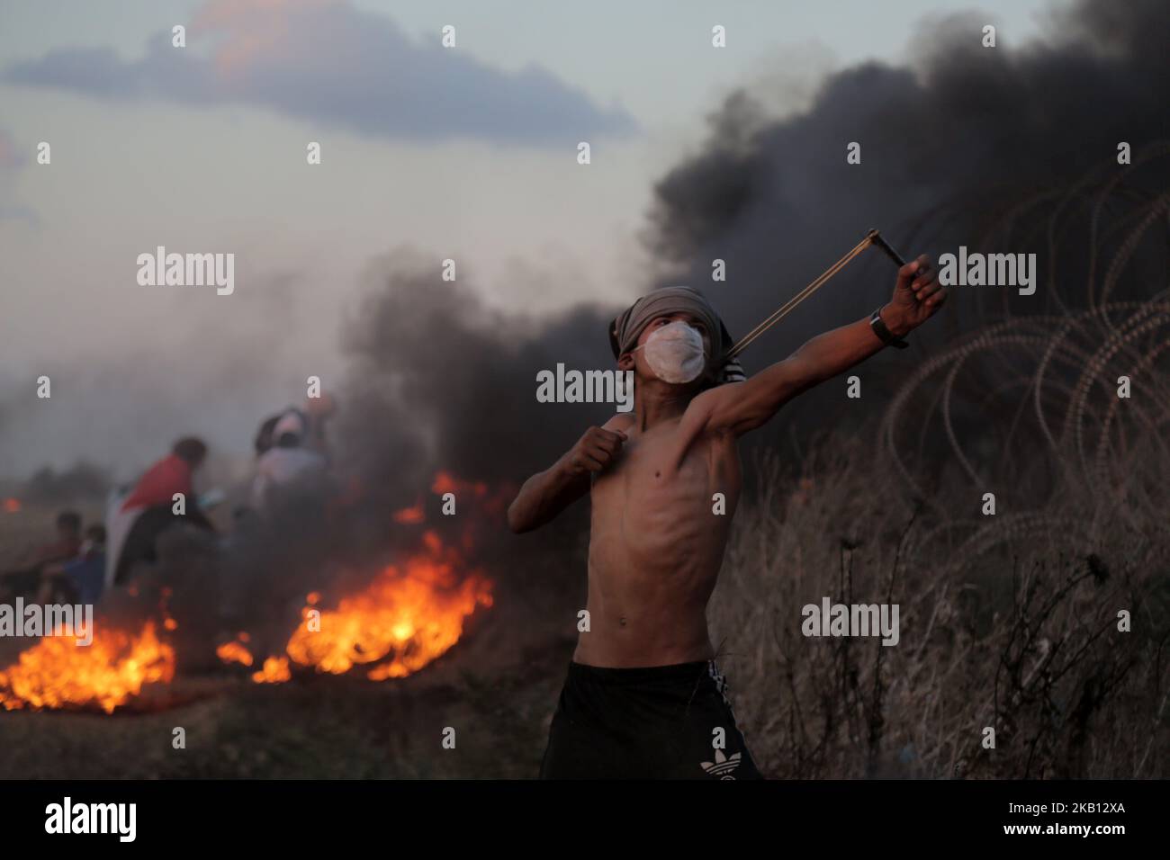 Un manifestant palestinien utilise un coup de feu pour jeter de la pierre vers les forces israéliennes tirant des gaz lacrymogènes lors d'une manifestation le long de la barrière israélienne à l'est de la ville de Gaza sur 14 septembre 2018. (Photo de Majdi Fathi/NurPhoto) Banque D'Images