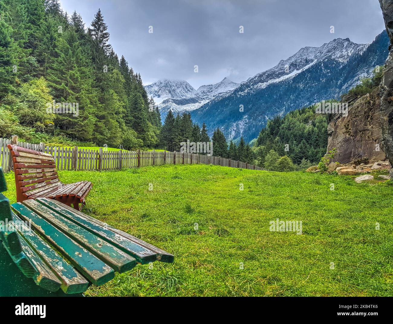 Deux bancs en bois debout sur un pré vert, en face des montagnes pittoresques des Alpes enneigées de Tirol, Autriche. Concept du tourisme Banque D'Images