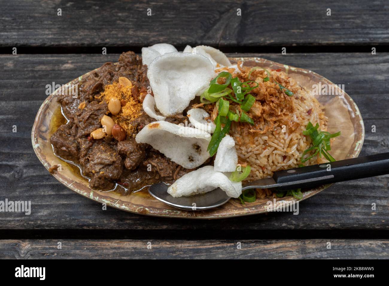 Renning Daging, ragoût de bœuf épicé indonésien, et riz frit épicé Nasi goreng, indonésien ou Bali sur une table en bois rugueuse. Banque D'Images
