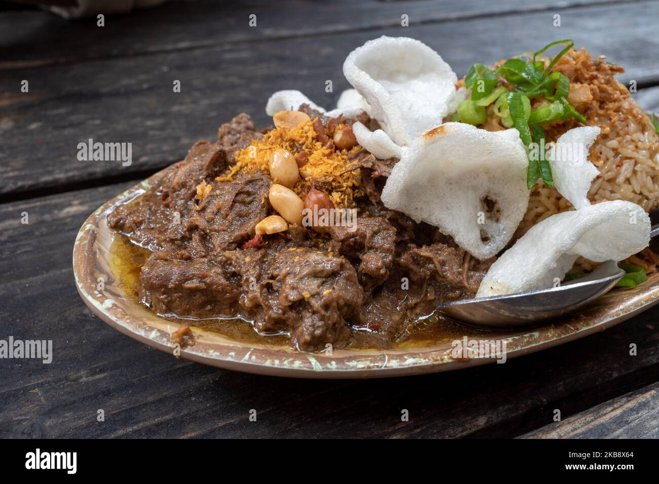 Renning Daging, ragoût de bœuf épicé indonésien, et riz frit épicé Nasi goreng, indonésien ou Bali sur une table en bois rugueuse. Banque D'Images