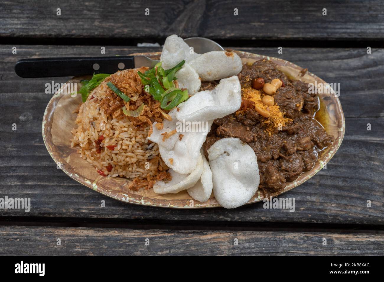 Renning Daging, ragoût de bœuf épicé indonésien, et riz frit épicé Nasi goreng, indonésien ou Bali sur une table en bois rugueuse. Banque D'Images