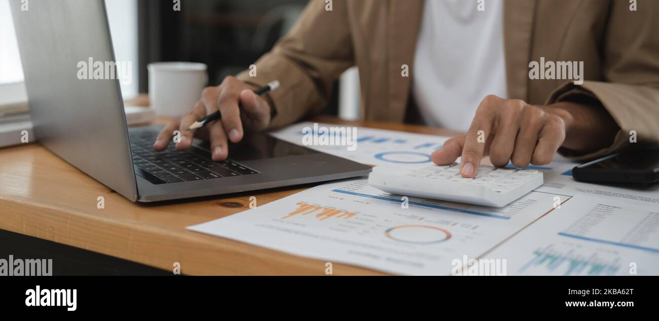 Gros plan homme travaillant sur la finance avec calculatrice à son bureau pour calculer les dépenses, concept de comptabilité Banque D'Images
