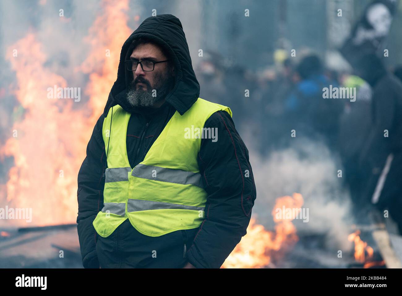 Un manifestant vêtu d'un gilet jaune se tient devant une barricade au feu  sur la place d'Italie, ce samedi, 16 novembre 2019, tandis que s'est  déroulé à Paris l'anniversaire des Vêtes jaunes