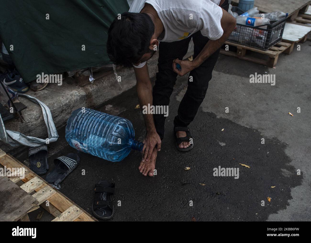 Un migrant d'Afghanistan se lavent les jambes, dix-huit (18) familles vivent dans des tentes d'été, totalement inadaptées aux mauvais temps des derniers jours, restent en dehors du camp d'Eleonas à Athènes, Grèce, le 18 novembre 2019. (Photo par Dimitris Lampropoulos/NurPhoto) Banque D'Images