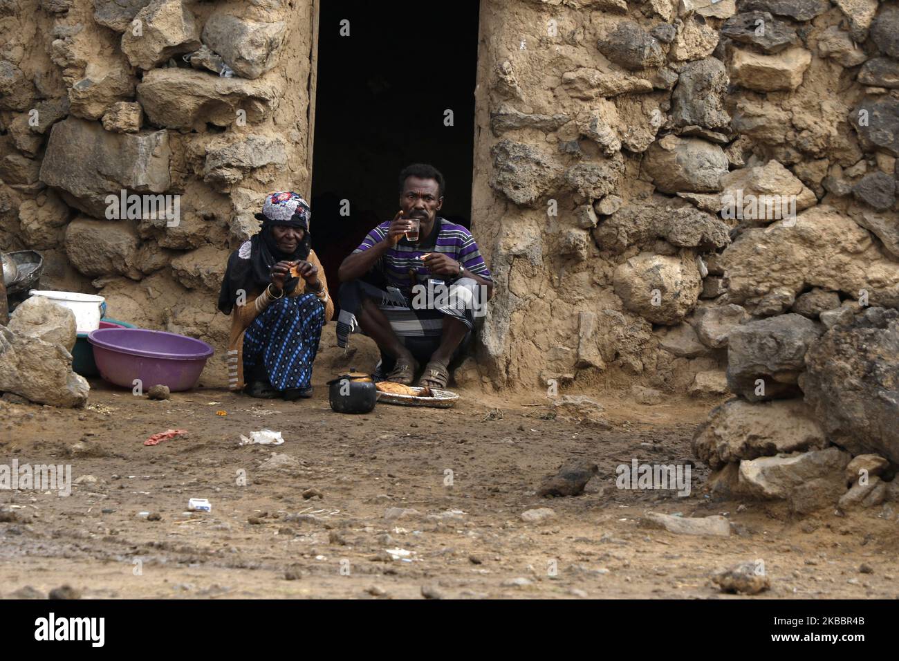 Un homme yéménite déplacé à l'intérieur du pays et sa femme qui ont fui leur maison en raison de la guerre en cours prennent leur petit déjeuner à l'extérieur de leur abri dans un camp de déplacés temporaires au nord de Sana'a, Yémen sur 26 novembre 2019. Le conflit dans la nation la plus pauvre du monde arabe a commencé avec la prise de pouvoir du Yémen central et du nord en 2014 par des rebelles alignés sur l'Iran, connus sous le nom de Houthis, qui ont fait sortir le gouvernement internationalement reconnu de la capitale, Sanaa. Quelques mois plus tard, en mars 2015, une coalition dirigée par l'Arabie saoudite a lancé sa campagne militaire aérienne. La guerre a tué plus de 10 000 000 personnes, et plus de trois millions l'ont été Banque D'Images