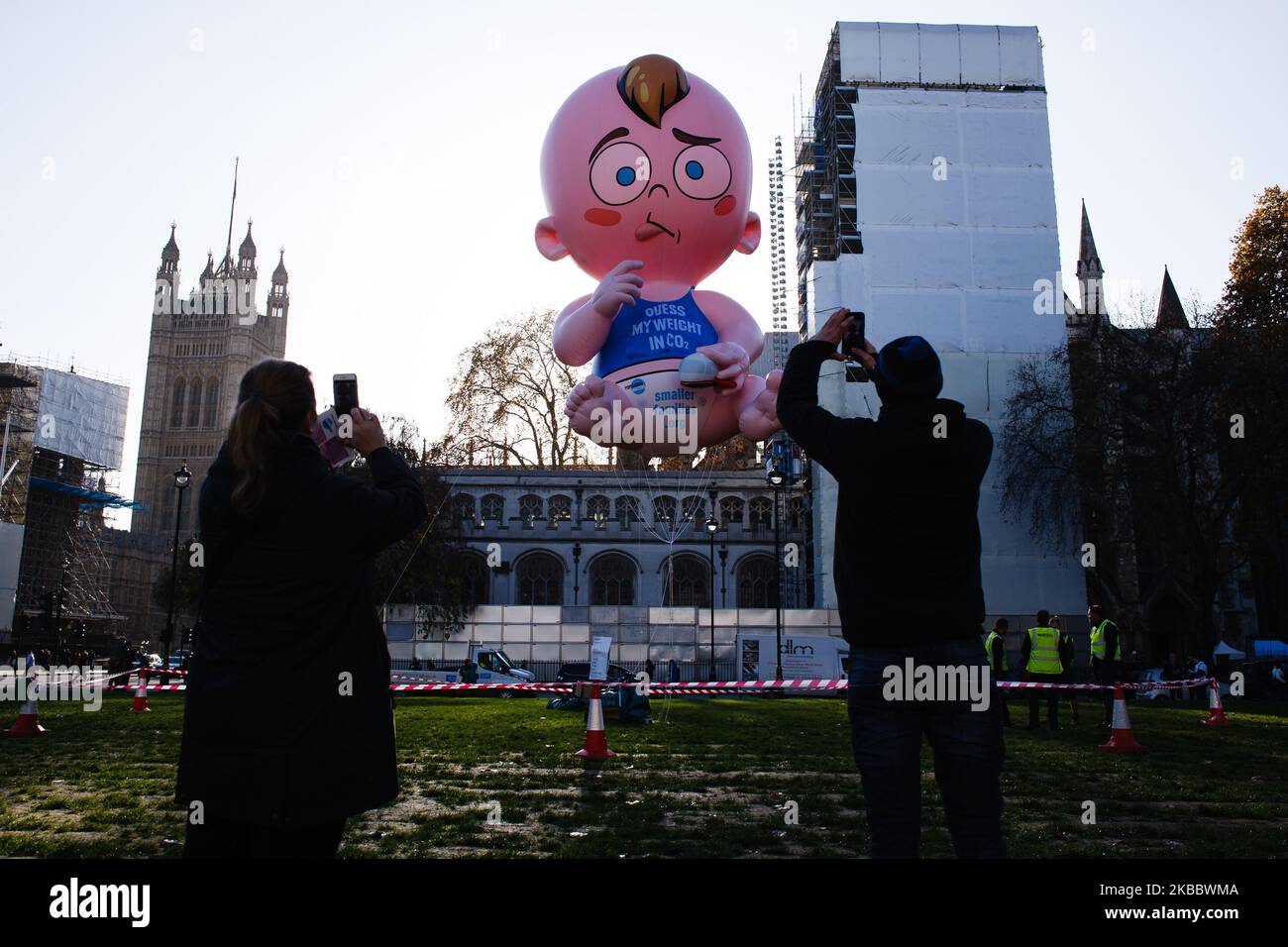 Les gens prennent des photos d'un « Big Baby » de 7 mètres de haut sur la place du Parlement lors de la dernière manifestation « Climate Strike » organisée par des écoliers à Londres, en Angleterre, sur 29 novembre 2019. Le Blimp a été organisé par la charité population Matters, afin de mettre en évidence le rôle de la population et de la taille de la famille dans la lutte contre la crise climatique. La manifestation d'aujourd'hui sur les frappes contre le climat approche la fin d'une année au cours de laquelle l'activisme climatique a pris le devant de la scène dans des villes du monde entier, sous la houlette du mouvement d'attaquant « Fridays for future » inspiré par Greta Thunberg et des activistes du Banque D'Images