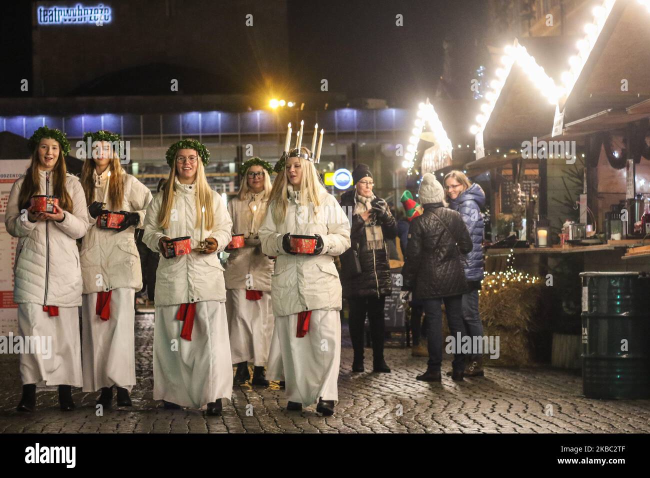 Les jeunes filles de Kalmar, Suède vêtues d'une robe blanche et d'une ceinture rouge (symbole du martyre) portent des bougies en procession le long de la foire de Noël de Gdansk dans la région du centre de la vieille ville sont vues à Gdansk, Pologne, le 2 décembre 2019 . L'un d'eux porte une couronne de bougies sur sa tête. Les filles vêtues de Sainte Lucy (Sankta Lucia) portent des biscuits en procession et chantent des chansons. Il est dit que célébrer avec vivile la Saint Lucy's Day aidera à vivre les longs jours d'hiver avec suffisamment de lumière. (Photo de Michal Fludra/NurPhoto) Banque D'Images