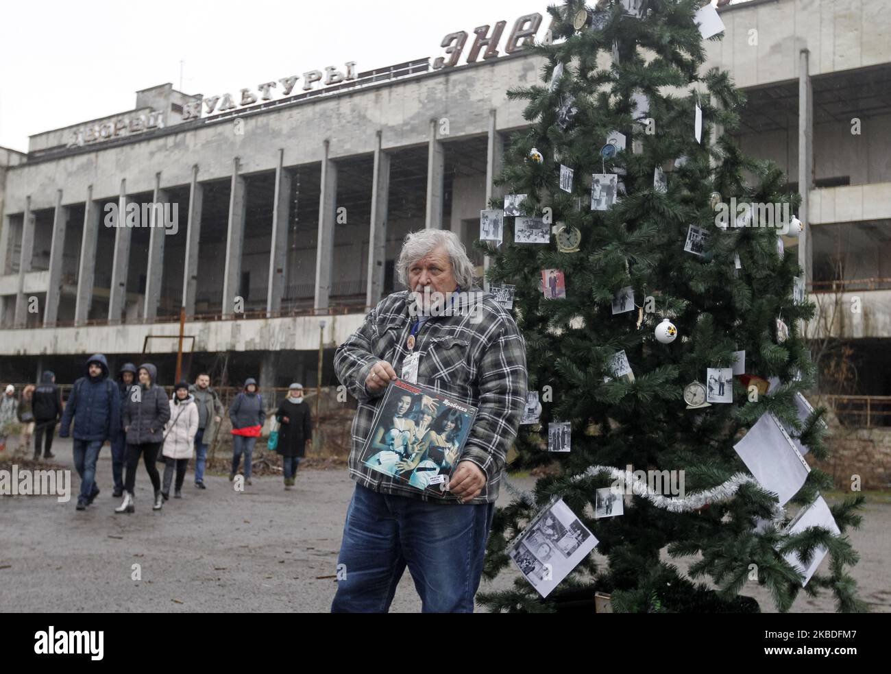 Un ancien résident de Pripyat montre ses assiettes préférées placées sur un arbre de Noël, sur une place principale de la ville de Pripyat, aujourd'hui abandonnée, à Tchernobyl, en Ukraine, le 25 décembre 2019. Les anciens habitants de Pripyat sont venus dans leur ville pour la première fois pour décorer avec leurs photos de famille un arbre de Noël, 33 ans après qu'ils ont quitté la ville après la catastrophe de Tchernobyl. Le dernier arbre de Noël a été installé à Pripyat le 1985 décembre. La catastrophe de Tchernobyl sur la centrale nucléaire de Tchernobyl s'est produite à 26 avril 1986. (Photo par STR/NurPhoto) Banque D'Images