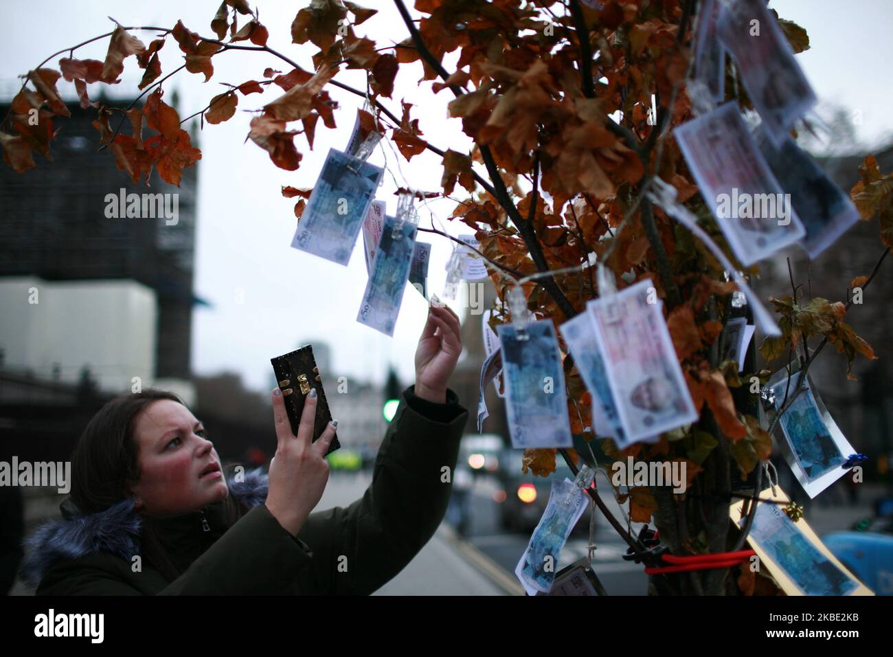 Une femme prend une photo de la spoof 'Bank of Brexitlies' 350m notes portant la face du Premier ministre Boris Johnson et du principal député Brexiteer Jacob Rees-Mogg attaché à un 'arbre de la Banque des Brexitlies' établi par des militants anti-Brexit devant le Parlement à Londres, en Angleterre, sur 7 janvier 2020. Lors de la campagne du référendum de 2016, les sortants ont faussement affirmé que 350m étaient envoyés chaque semaine dans l'UE, ce qui pourrait être dépensé au service national de santé. Le Royaume-Uni est sur le point de quitter l'UE à 11pm ans sur 31 janvier, en commençant une période de transition qui va jusqu'à la fin de l'année, à l'époque de Premier Ministre Banque D'Images